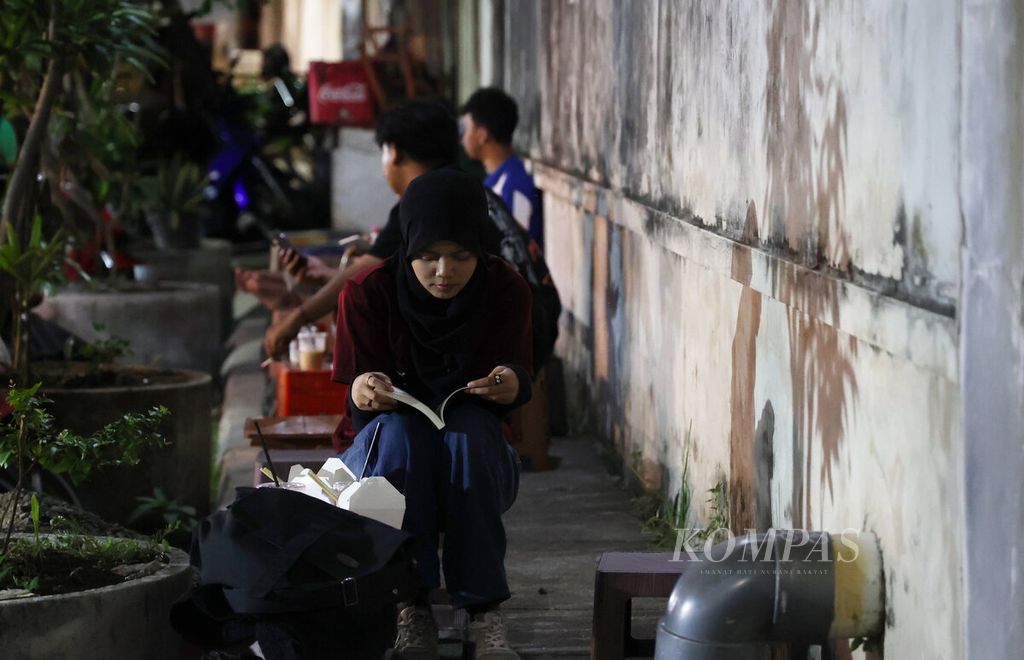 Pengunjung menikmati suasana menjelang malam dengan membaca buku dengan mengunjungi sebuah kedai di Jalan Pekojan, Kota Semarang, Jawa Tengah, Senin (15/9/2025). 
