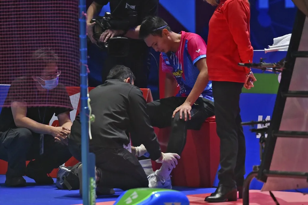 Pemain bulu tangkis Indonesia, Mohammad Ahsan (tengah), mendapat perawatan medis saat dia dan pasangan gandanya, Hendra Setiawan, berlaga melawan Bagas Maulana/Muhammad Shohibul Fikri, pada laga final All England, Minggu (20/3/2022). 