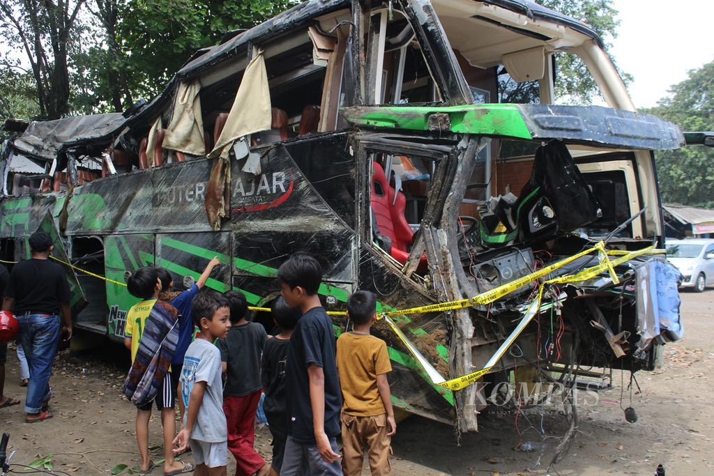 Anak-anak mengamati bus yang rusak akibat kecelakaan yang diparkir di Terminal Subang, Jawa Barat, Minggu (12/5/2024). Bus yang membawa rombongan dari SMK Lingga Kencana, Depok, ini  terguling dalam perjalanan pada Sabtu (11/5/2024) petang dan menewaskan 11 orang.