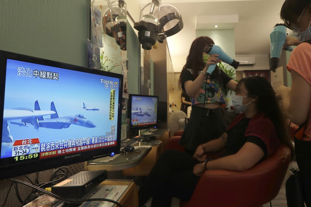 Seorang pelanggan tengah mendapat pelayanan di sebuah salon kecantikan di Taipei, Taiwan, sekaligus melihat tayangan berita di televisi tentang perkembangan situasi di Selat Taiwan, Kamis (4/8/2022). (AP Photo/Chiang Ying-ying)