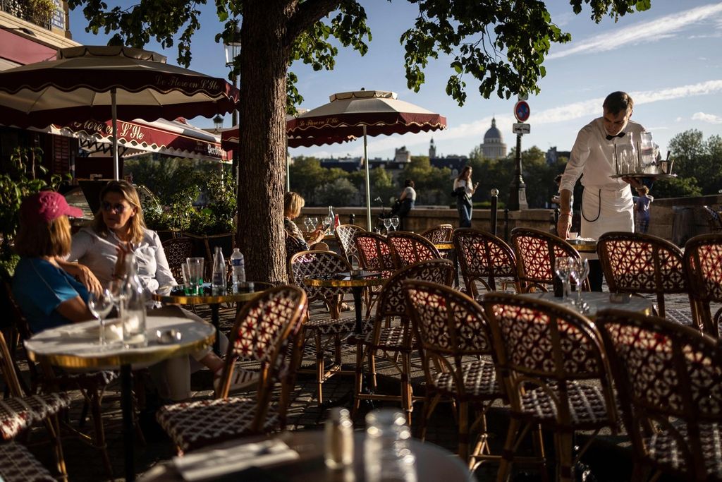 Seorang pelayan membersihkan meja di kafe Flore en lIle, salah satu lokasi ikonik yang muncul pada serial Netflix, <i>Emily in Paris,</i> di Paris, Perancis, 27 Agustus 2024. 
