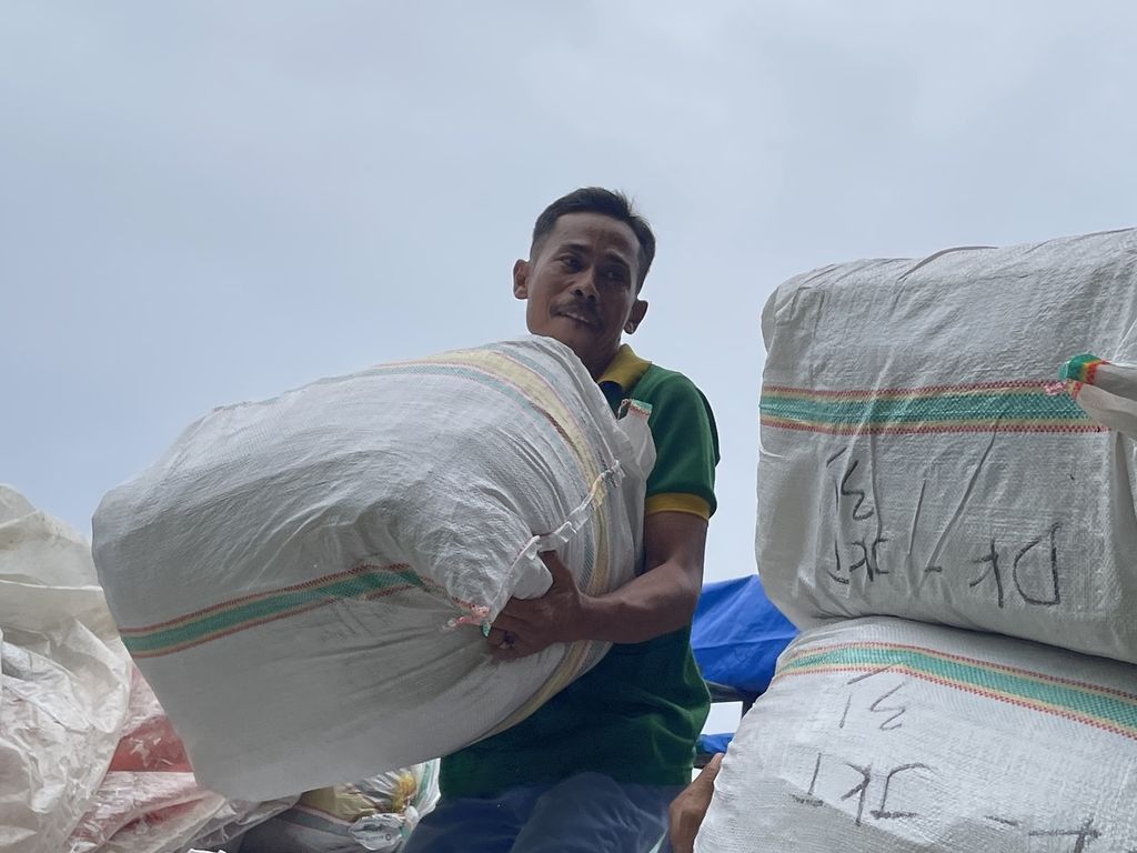 Santibi (43) mengangkut sekarung sayuran di Pasar Induk Kramat Jati, Jakarta Timur, Rabu (8/3/2023).
