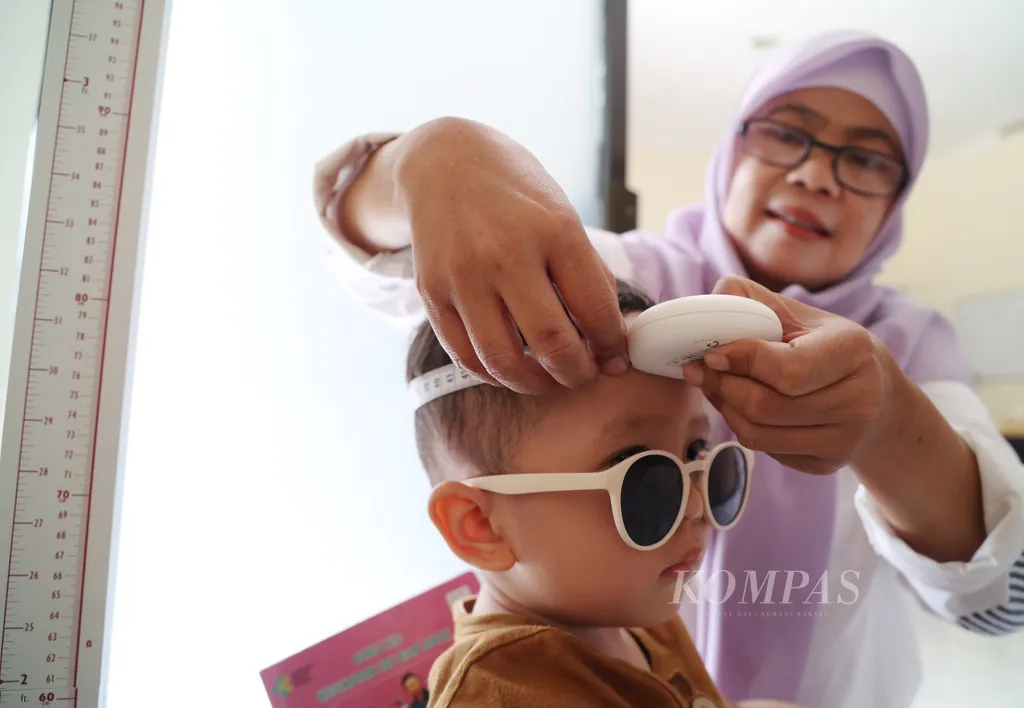 Kader posyandu mengukur lingkar kepala seorang balita di Posyandu Koi, Pamulang Timur, Tangerang Selatan, Banten, Jumat (20/9/2024). Posyandu diamanfaatkan untuk mendapatkan layanan kesehatan dan penyuluhan gizi bagi ibu dan anak yang bertujuan salah satunya mencegah stunting (tengkes) pada anak. Merujuk pada data Survei Kesehatan Indonesia (SKI) 2023, angka tengkes kini masih sebesar 21,6 persen. Itu artinya, satu dari lima anak di Indonesia mengalami tengkes. Angka ini menempatkan Indonesia pada posisi ke-27 negara dengan angka tengkes tertinggi dari 154 negara di dunia. Kompas/Hendra A Setyawan (HAS)