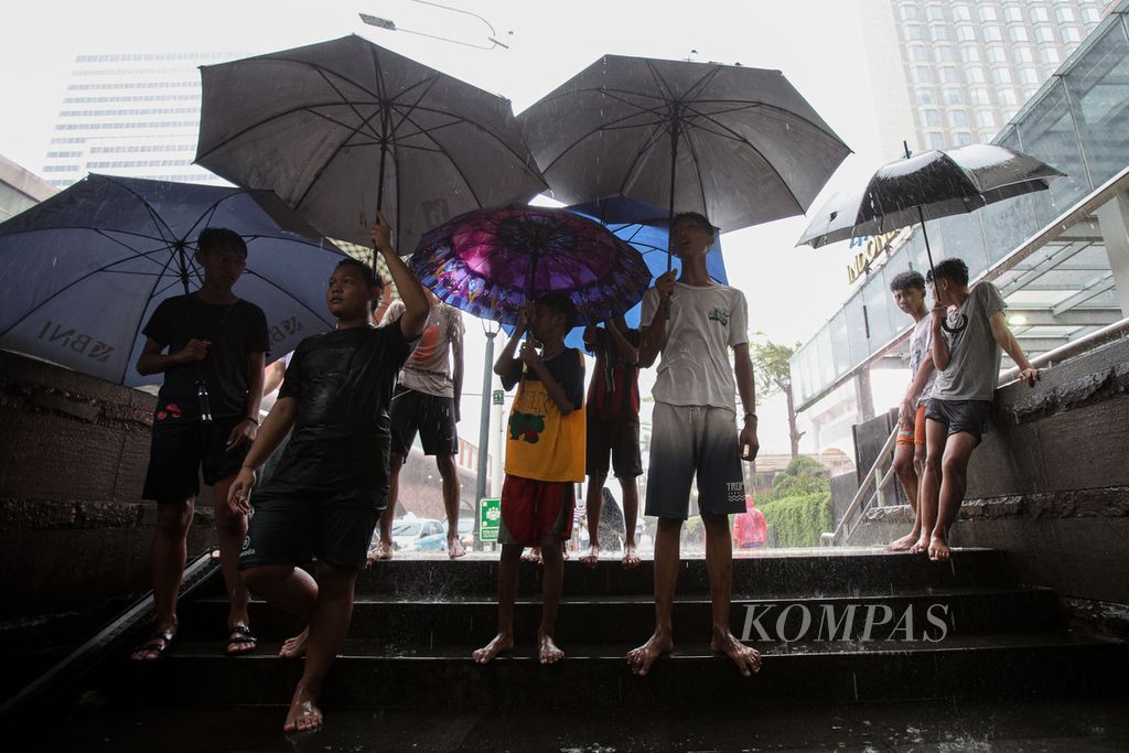 Para ojek payung menunggu warga menggunakan jasa mereka di depan Stasiun MRT Bundaran Hotel Indonesia (HI), Jakarta, Minggu (3/11/2024). 