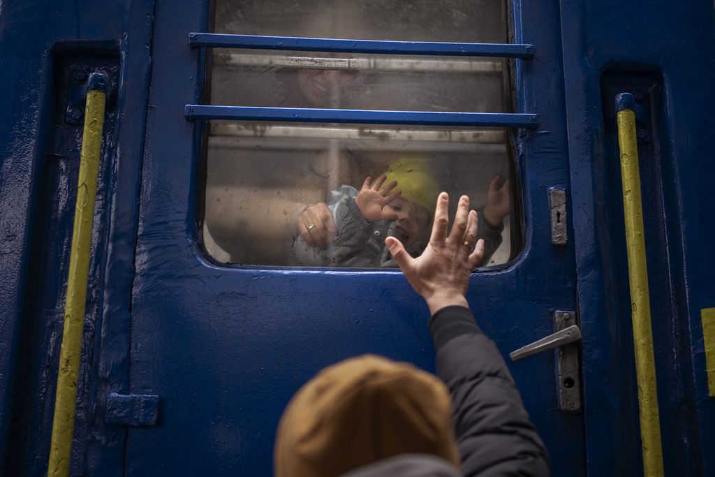 Stanislav (40), membelakangi lensa, melambaikan tangannya pada putranya, David (2), dan sang istri, Anna (35), yang melihatnya dari dalam kereta yang akan berangkat dari Kiev ke Lviv, Ukraina, Kamis (3/3/2022). Anggota keluarga laki-laki yang telah berusia dewasa memilih bertahan di Ukraina untuk membantu militer mempertahankan negaranya dari serbuan Rusia.
