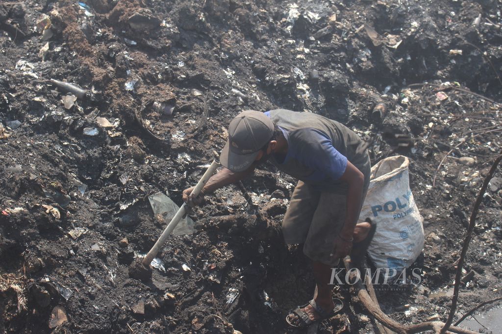 Seorang pemulung sedang mengambil beberapa barang di tempat pembuangan sampah ilegal yang terbakar di Desa Sumber Jaya, Kecamatan Tambun Utara, Kabupaten Bekasi, Selasa (26/9/2023). 