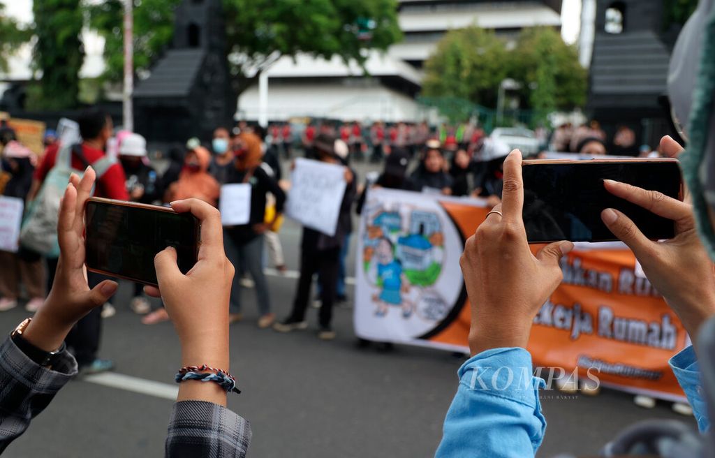 Peserta aksi mengabadikan rekan mereka yang menggelar unjuk rasa dalam memperingati Hari Perempuan Internasional di depan Kantor DPRD Jawa Tengah, Kota Semarang, Rabu (8/3/2023). Mereka melakukan aksi solidaritas untuk menyuarakan berbagai persoalan tentang isu perempuan dalam berbagai sektor, antara lain sosial, budaya, ekonomi, lingkungan, dan politik. 