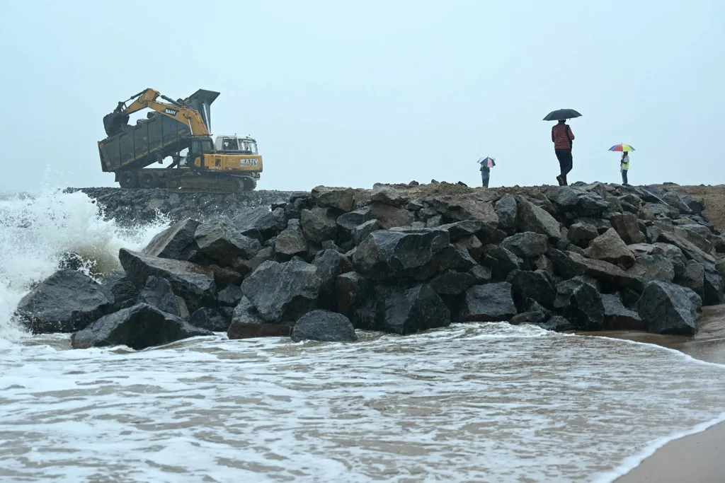 An excavator places stones to curb sea erosion at a coastal village near Mahabalipuram on the outskirts of Chennai on November 26, 2024. The initiative aims to protect the coastal area from further damage caused by strong waves and rising sea levels. (Photo by R.Satish BABU / AFP)