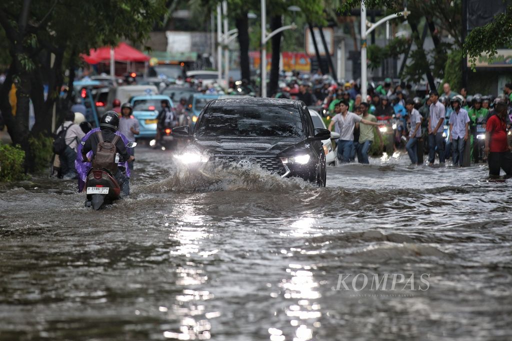 Sebuah mobil menerobos genangan air di Jalan Kemang Raya, Jakarta Selatan, Selasa (5/11/2024).  