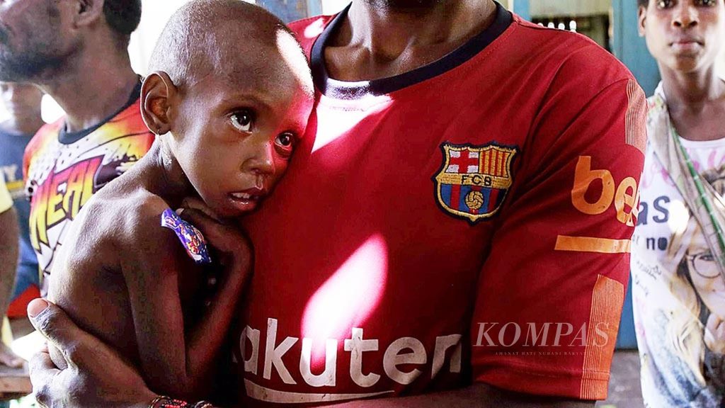 Maria Samaor (3) digendong ayahnya saat menunggu pembagian makanan tambahan berupa biskuit untuk anak-anak dari Tim Terpadu Penanggulangan KLB Campak dan Gizi Buruk di Kampung Atat, Distrik Pulau Tiga, Kabupaten Asmat, Papua, Sabtu (13/1).