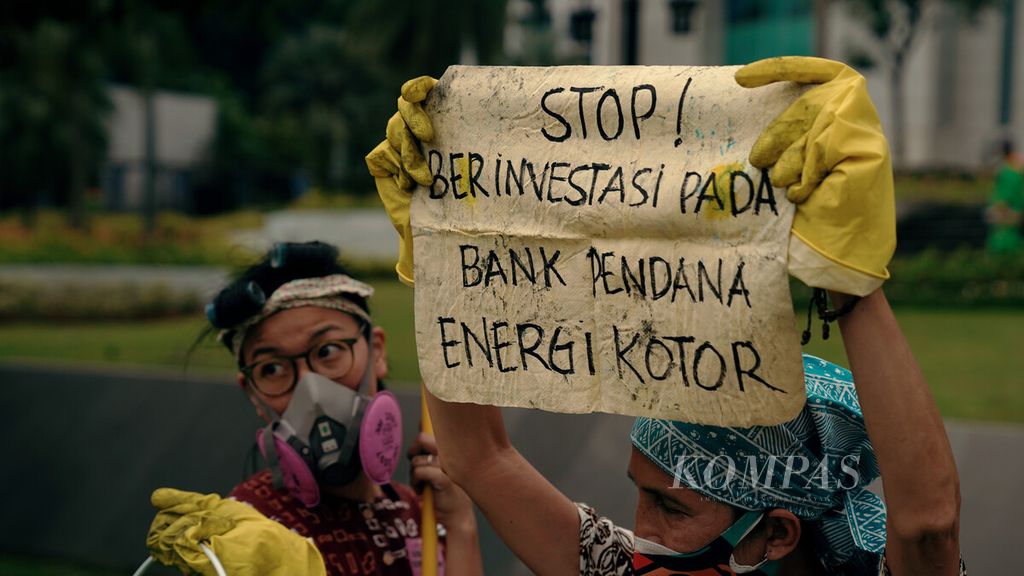 Aktivis Jeda untuk Iklim aksi bersih-bersih energi kotor dari batubara di depan Kantor Pusat Bank Mandiri, Jakarta, Selasa (25/1/2022). Aksi ini mengingatkan kepada lembaga keuangan untuk segera melepaskan diri dari lingkaran bisnis energi batubara. Salah satu target aksi iklim Pemerintah Indonesia untuk <i>net zero emission</i> lebih cepat dari tahun 2060, tetapi sejumlah bank masih tetap memberikan pembiayaan pada sektor energi penyumbang emisi terbesar, yaitu batubara. 