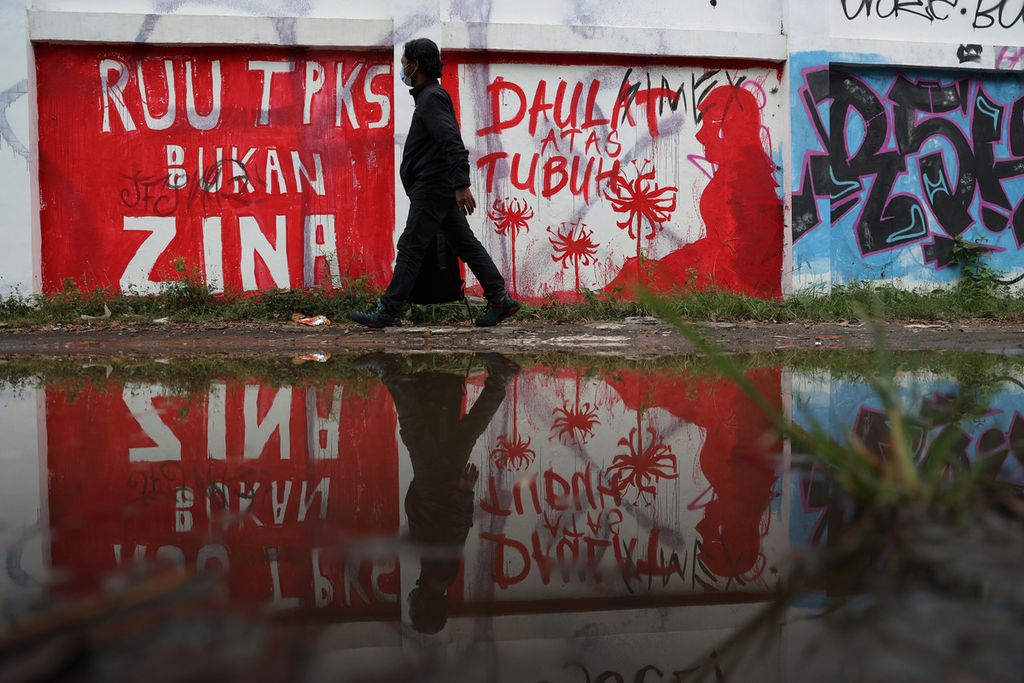 Warga melintas di depan mural berisi seruan untuk mendorong pengesahan Rancangan Undang-Undang Tindak Pidana Kekerasan Seksual yang dibuat di tembok Stadion Kridosono, Yogyakarta, Senin (10/1/2021). Berbagai elemen masyarakat terus menyuarakan urgensi pengesahan RUU TPKS melalui bermacam media seiring terus berulangnya kemunculan kasus kekerasan seksual, terutama terhadap perempuan dan anak-anak.