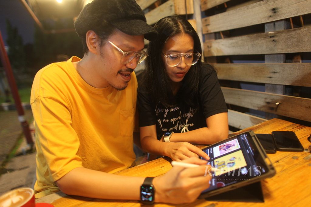 Rhesa Aditya dan Endah Widiastuti menunjukkan karya berwujud digital yang dijual di lokapasar non-fungible token (NFT). Duo Endah N Rhesa ini memasarkan produk berupa ilustrasi dari interpretasi lagu mereka, fotografi, juga animasi sampul album berlatar musik di rantai blok Tezos. NFT menjadi medium baru bagi mereka menyebarkan karya musik dan selingkungnya. Foto diambil pada Jumat (17/6/2022) di Pamulang, Tangerang Selatan, Banten.
