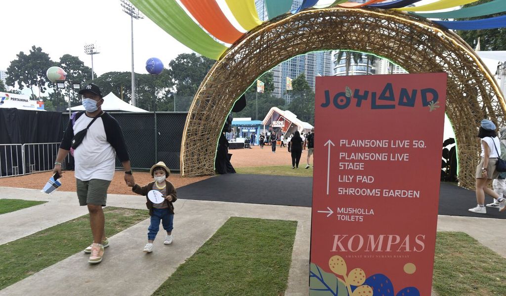 Pengunjung terlihat membawa anak-anak pada hari pertama Joyland Festival 2022 yang berlangsung di Stadion Softball Gelora Bung Karno, Jakarta, Jumat (4/11/2022). Hujan deras yang turun sejak sore membuat penampilan sejumlah pengisi acara mundur dari jadwal semula.