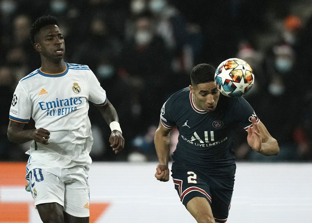 Penyerang Real Madrid, Vinicius Junior (kiri), gagal merebut bola yang dikuasai bek Paris Saint-Germain (PSG), Achraf Hakimi, pada laga pertama babak 16 besar Liga Champions di Stadion Parc des Princes, Paris, Perancis, Rabu (16/2/2022) dini hari WIB. Gol kemenangan PSG tercipta pada menit terakhir babak kedua berkat aksi individu Kylian Mbappe menerobos barisan pertahanan Madrid dan menaklukkan kiper Thibaut Courtois.