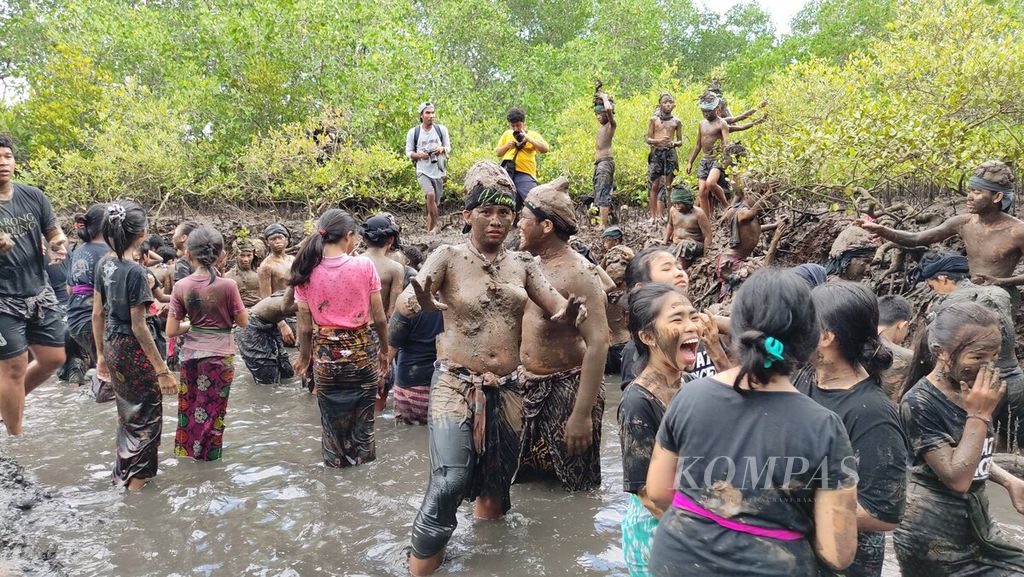 <i>Krama</i> (warga) dan <i>yowana</i> (pemuda dan pemudi) Desa Adat Kedonganan, Kedonganan, Kuta, Kabupaten Badung, saling membalurkan lumpur hutan bakau ketika mengikuti tradisi <i>mabuug-buugan</i> di tengah hutan mangrove Taman Hutan Raya Ngurah Rai, Kamis (23/3/2023).
