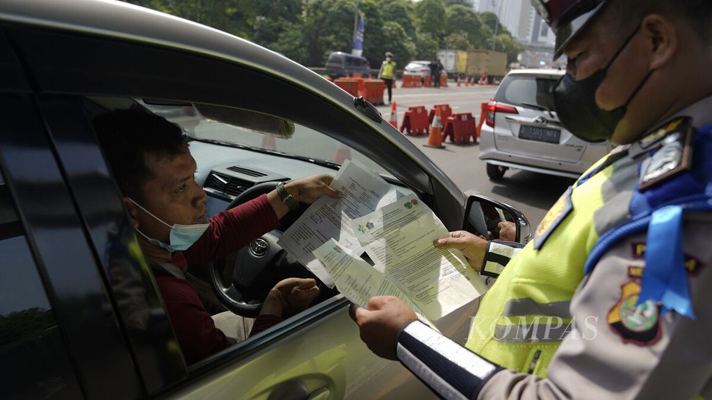 Polisi memeriksa surat kelengkapan dokumen dalam penyekatan arus mudik kendaraan di Jalan Tol Cikampek KM 31, Cikarang Barat, Kabupaten Bekasi, Jawa Barat, Kamis (6/5/2021).