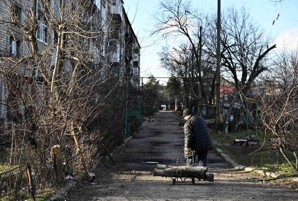 Seorang warga membawa sebatang kayu yang akan digunakan untuk kebutuhan memasak dan menghangatkan diri di tempat tinggalnya di Lyman, Donetsk, Ukraina, Rabu (14/12/2022).