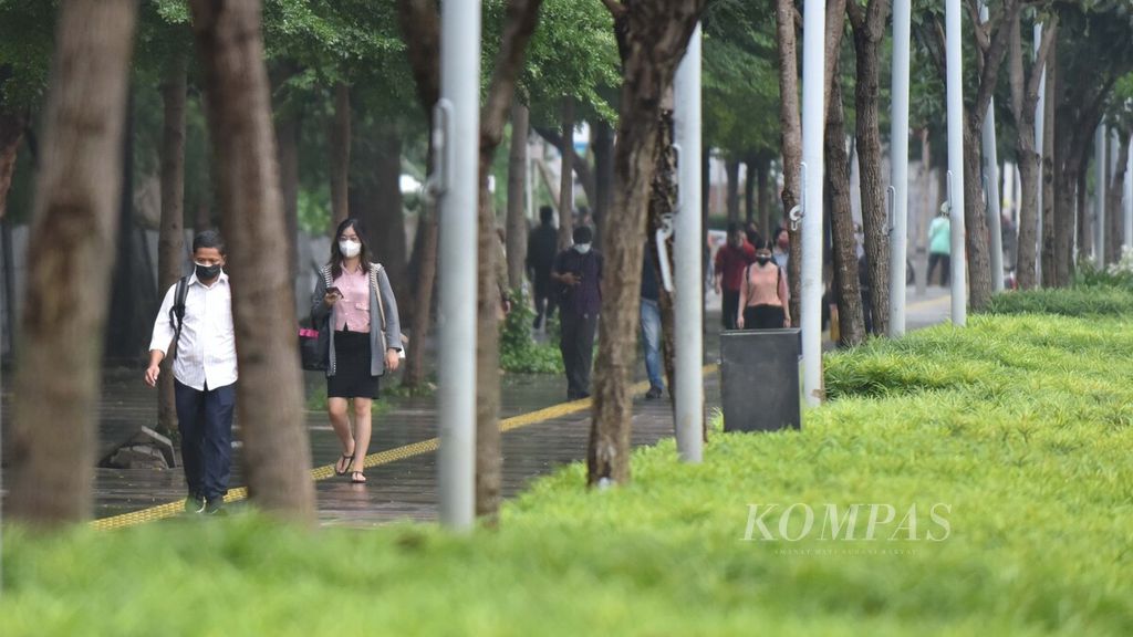 Pejalan kaki melintasi deretan pohon peneduh di Jalan Jenderal Sudirman, Jakarta, Rabu (15/12/2021). Banyaknya pohon yang menaungi trotoar di kawasan tersebut bisa membuat kualitas udara tetap terjaga. Trotoar yang selesai direvitalisasi menjelang perhelatan Asian Games 2018 itu diharapkan bisa mendorong minat masyarakat untuk berjalan kaki dan menggunakan transportasi umum.