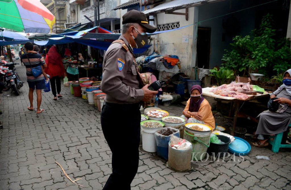 Salah satu petugas memberikan edukasi bagi pedagang dan pengunjung untuk selalu waspada terhadap penularan Covid-19 di Pasar Prembaen, Kota Semarang, Jawa Tengah, Jawa Tengah, Selasa (12/1/2021).  Pasar menjadi salah satu tempat dengan interaksi sosial tinggi di tengah pandemi ini. Selain itu  petugas juga  berpatroli untuk memastikan berjalannya pembatasan sosial dan pelaksanaan protokol kesehatan.