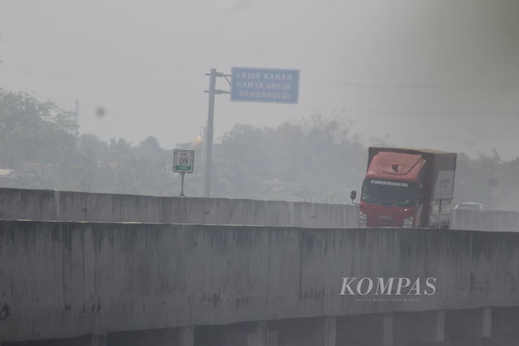 Lalu lintas di ruas Jalan Tol Cibitung-Cilincing diselimuti asap akibat kebakaran tempat pembuangan sampah ilegal di Desa Sumber Jaya, Kecamatan Tambun Utara, Kabupaten Bekasi, Selasa (26/9/2023). Kebakaran menghanguskan sekitar 1 hektar lahan.