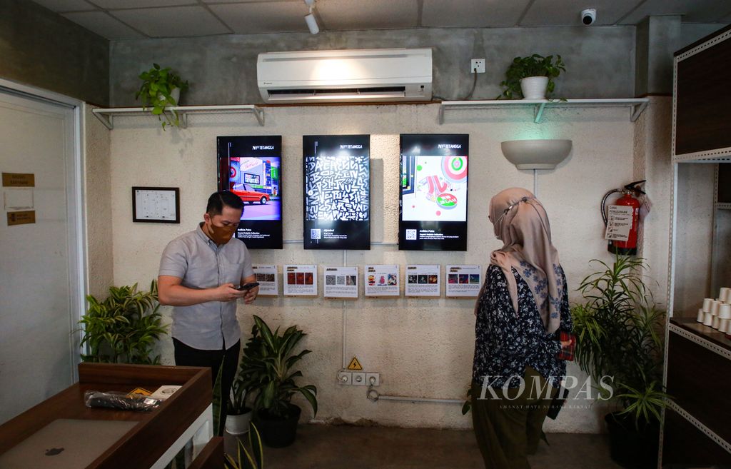 Pengunjung menyaksikan karya NFT, singkatan dari <i>non-fungible token</i> di gerai kopi di kawasan Bintaro, Pondok Aren, Tangerang Selatan, Banten, Rabu (24/8/2022). Pameran kolektif NFTetangga ini diikuti oleh tujuh orang kreator yang tinggal dan berkarya di Bintaro. Pemeran akan berlangsung hingga 22 September 2022.