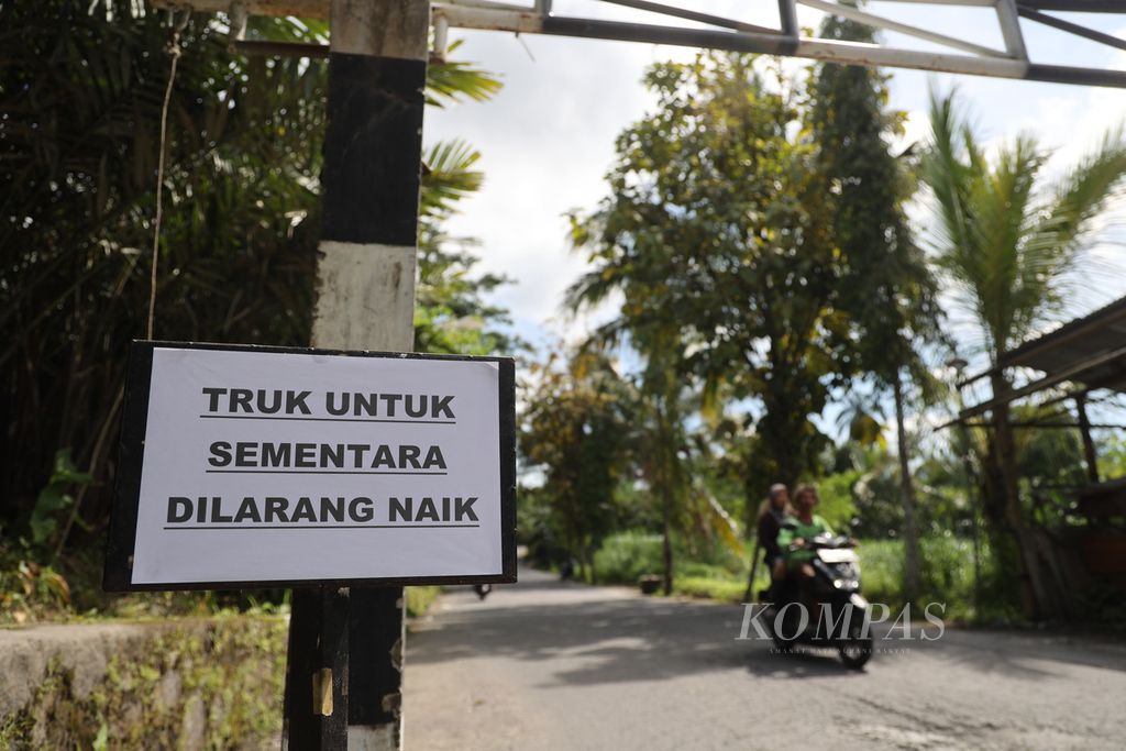 Kertas dengan tulisan informasi pengumuman larangan bagi truk penambang pasir melintas dipasang di Desa Kaliurang, Srumbung, Magelang, Jawa Tengah, Minggu (12/3/2023). 