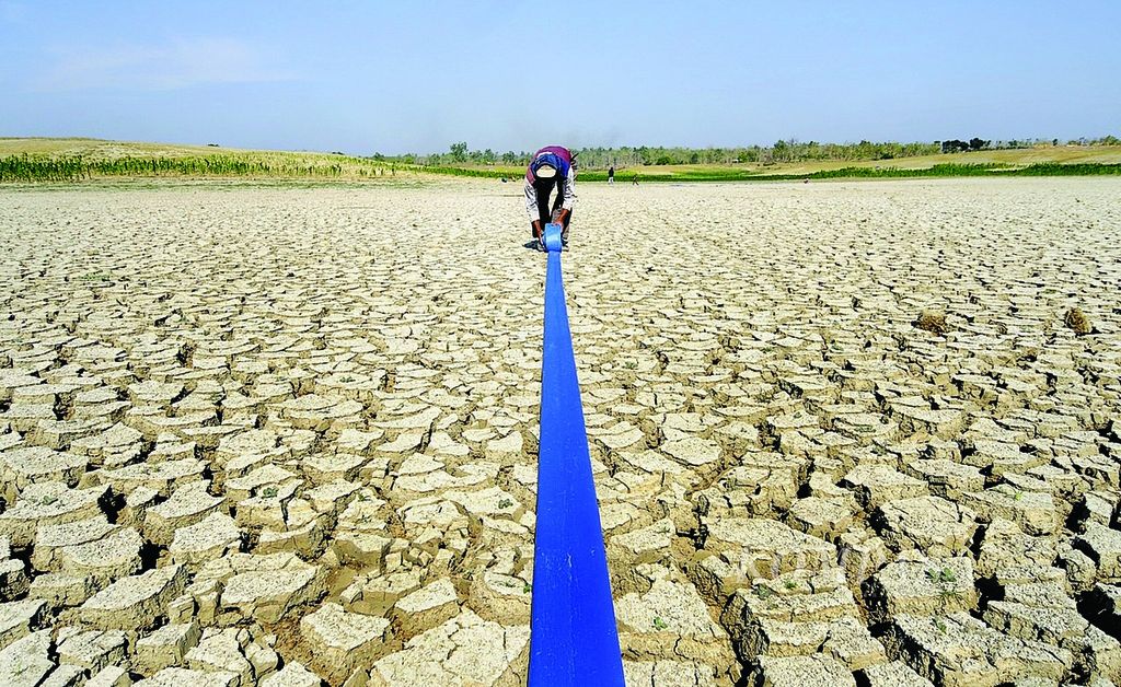 Seorang warga menggulung selang air di dasar Waduk Prijetan yang mengering di Kecamatan Kedungpring, Lamongan, Jawa Timur, Selasa (4/9), usai menyirami kebun jagungnya yang berada di sekitar waduk tersebut. Kemarau membuat air di waduk tersebut nyaris kering dan sudah tidak bisa mengairi pertanian di desa-desa di sekitarnya.