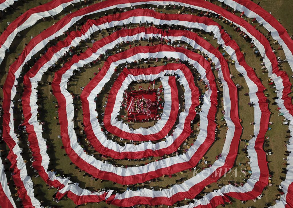 Pelajar berbusana adat membawa bendera merah putih sepanjang 2.000 meter dalam rangkaian Sumpah Merah Putih di area Tugu Pahlawan, Surabaya, Jawa Timur, Sabtu (26/10/2019). Kegiatan yang diselenggarakan dalam rangka menyambut Hari Sumpah Pemuda 28 Oktober ini diisi dengan pentas sosio drama Kita Merah Putih, pembacaan Sumpah Merah Putih yang dipimpin Walikota Surabaya Tri Rismaharini dan kirab bendera merah putih. Kegiatan ini untuk mengingatkan generasi muda agar menjaga kebhinekaan dalam mengisi kemerdekaan.