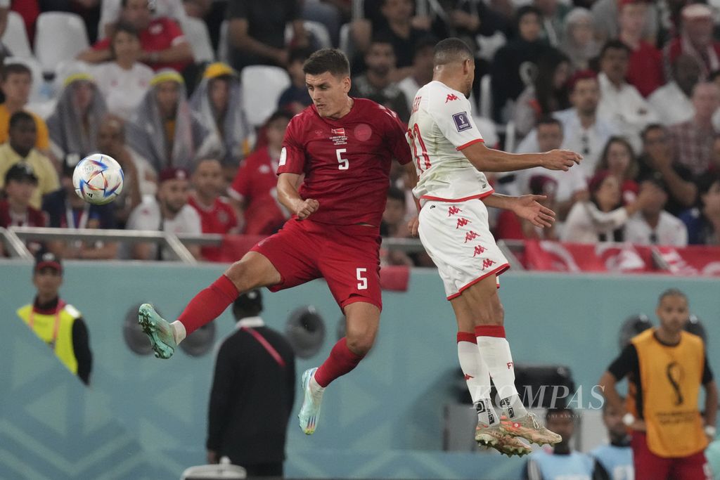 Pemain Denmark Joakim Maehle berebut bola dengan pemain Tunisia Taha Yassine Khenissi saat bertanding di babak fase grup C Piala Dunia 2022 di Stadion Education City, Qatar, Selasa (22/11/2022). Pertandingan berakhir imbang 0-01. 