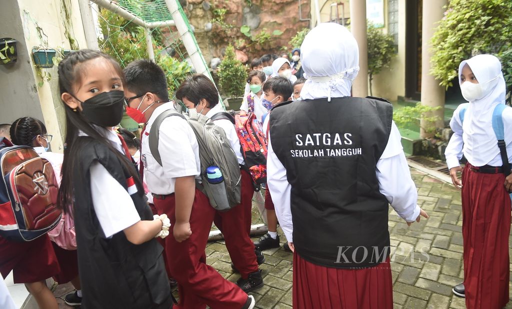 Satgas Sekolah Tangguh mengawasi Siswa yang pulang sekolah di SD Negeri Kaliasin 01, Surabaya, Jawa Timur, Senin (10/1/2022). Pemerintah Kota Surabaya mulai melaksanakan pembelajaran tatap muka atau PTM 100 persen bagi PAUD, TK, SD dan SMP pada 10 Januari 2022 ini. PTM 100 persen minggu pertama dibagi dua shift, yakni pagi dan siang. Tiap shift 50 persen. 