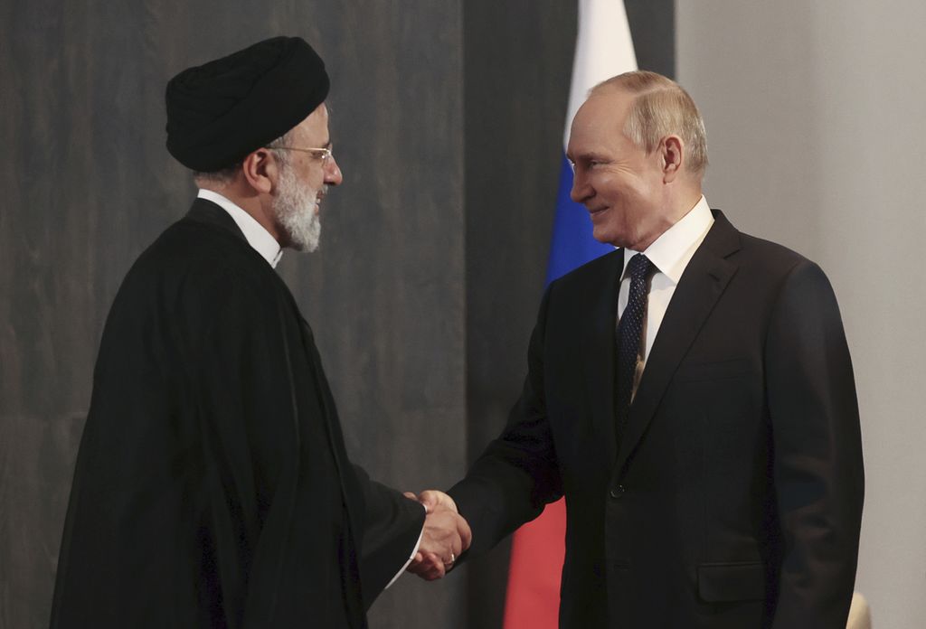 Presiden Rusia Vladimir Putin (kanan,) dan Presiden Iran Ebrahim Raisi berjabat tangan selama pertemuan mereka di sela-sela KTT Organisasi Kerja Sama Shanghai (SCO) di Samarkand, Uzbekistan, Kamis (15/9/2022).
