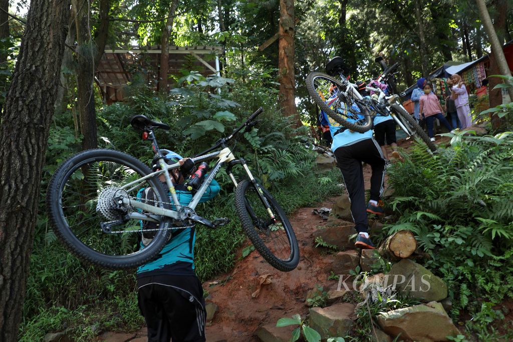 Pesepeda memanggul sepeda saat melintasi jalur di Taman Kota 2 BSD, Tangerang Selatan, Banten, Minggu (8/5/2022). Pada libur Lebaran seperti saat ini, taman kota yang baru selesai direvitalisasi dan dipercantik ini menjadi salah satu lokasi favorit warga Tangerang Selatan untuk jalan-jalan bersama keluarga atau sekadar olahraga.