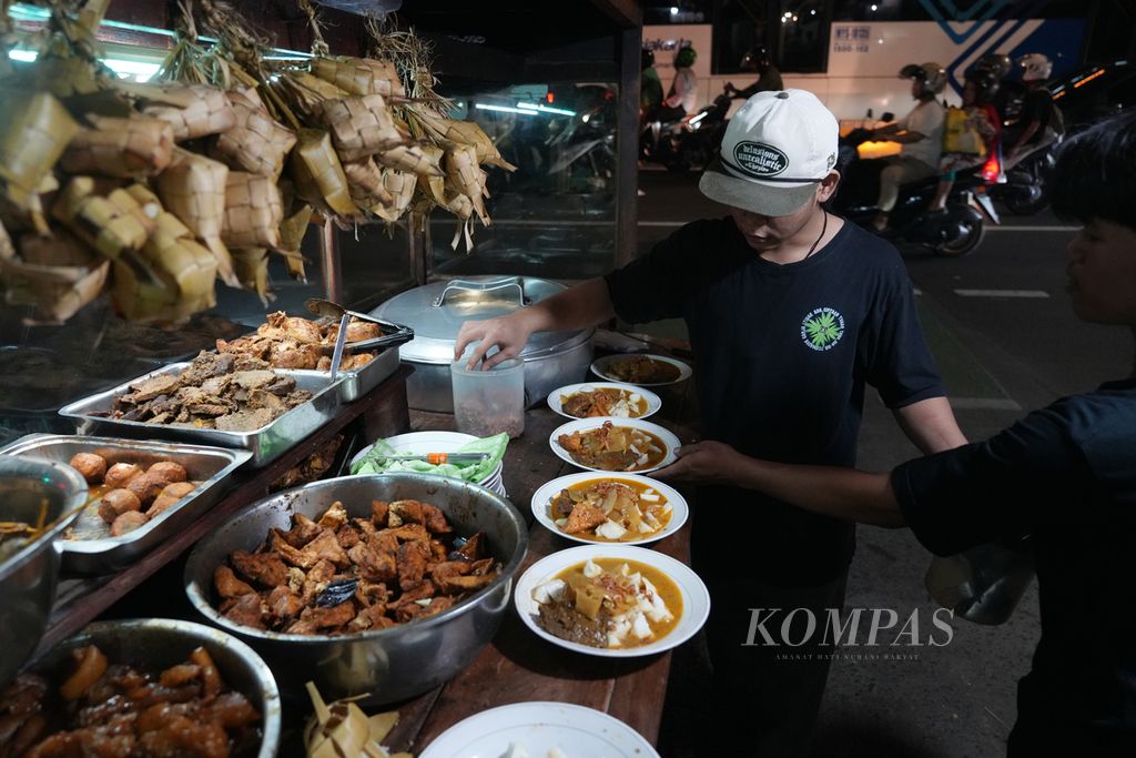 Penjual melayani pembeli Ketupat Sayur Mandala di Jalan Mampang Prapatan, Jakarta Selatan, Rabu (13/11/2024). Warung ketupat sayur tersebut buka dari pukul 18.00 WIB pukul 04.00 WIB. Dalam sehari sebanyak 600-700 porsi habis terjual. Ada enam pilihan menu ketupat sayur di warung tersebut.