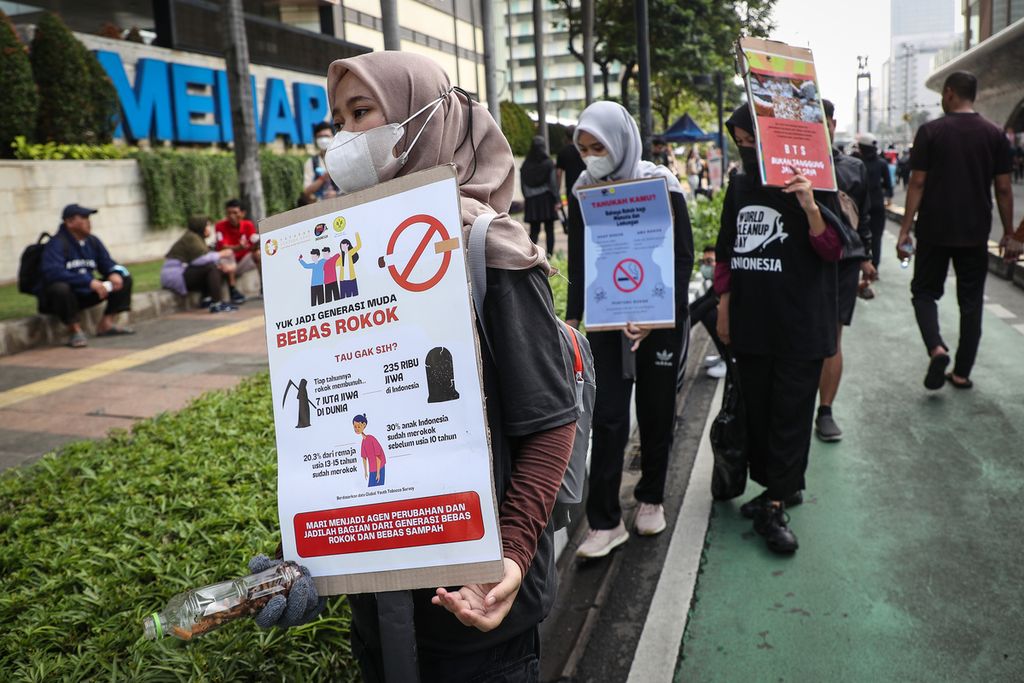 Sukarelawan membawa poster bahaya rokok dalam kegiatan "Plogging Cigarette Butt" di kawasan Bundaran HI, Jakarta, Minggu (28/5/2023). World Cleanup Day (WCD) Indonesia dan Yayasan Lentera Anak mengampanyekan dampak buruk rokok terhadap kesehatan dan lingkungan untuk menyambut Hari Tanpa Tembakau Sedunia yang diperingati setiap tanggal 31 Mei. Dalam kegiatan tersebut, sekitar 100 relawan memungut sampah puntung rokok di area hari bebas kendaraan bermotor atau car free day sembari membawa poster yang menyuarakan dampak buruk rokok.