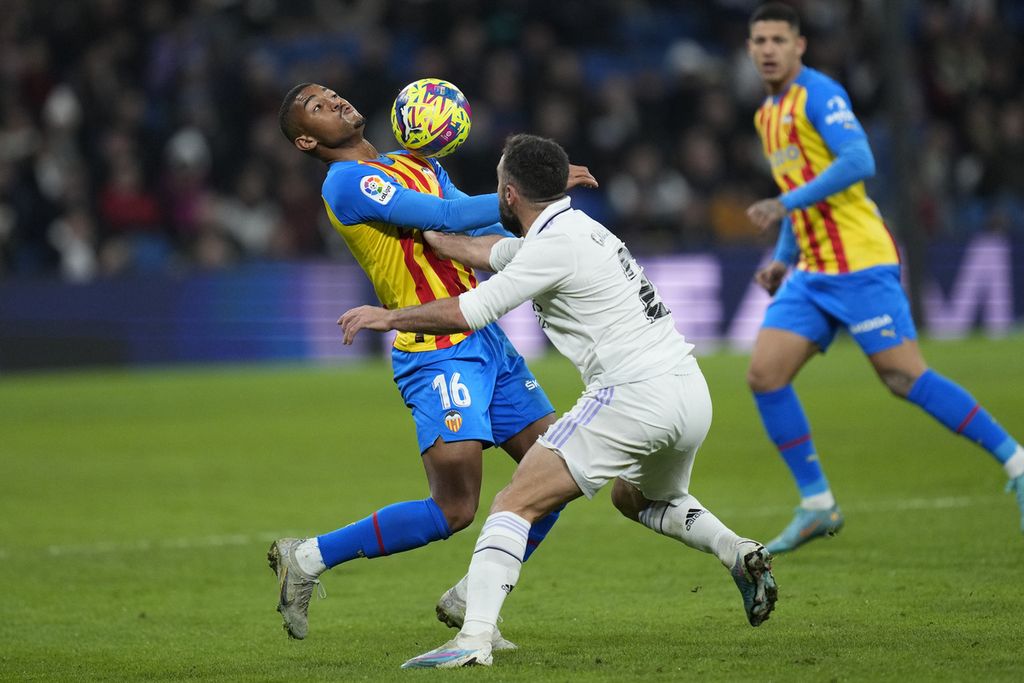 Pemain Valencia, Samuel Lino (kiri), berduel dengan bek Real Madrid, Dani Carvajal (tengah), dalam laga Liga Spanyol antara Real Madrid dan Valencia di Stadion Santiago Bernabeu di Madrid, 2 Februari 2023. Real akan berlaga pada Piala Dunia Antarklub di Maroko.