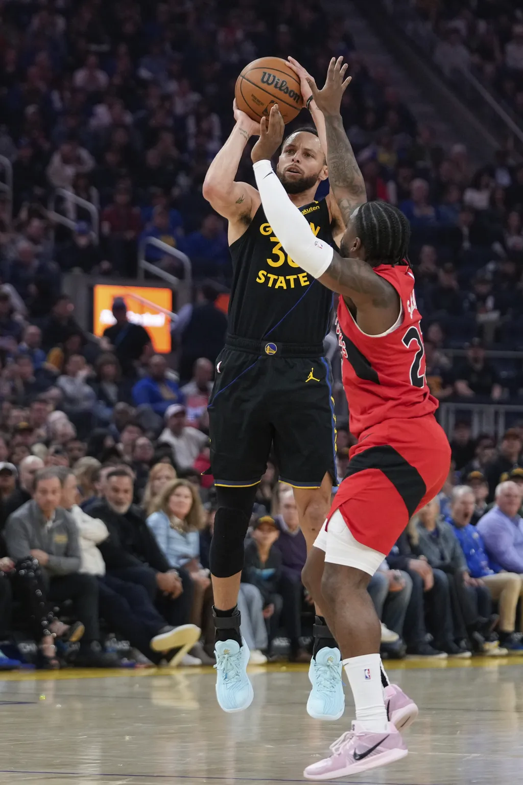 Golden State Warriors guard Stephen Curry, left, shoots a 3-point basket in front of Toronto Raptors guard Jamal Shead during the first half of an NBA basketball game Thursday, March 20, 2025, in San Francisco. (AP Photo/Godofredo A. Vásquez)