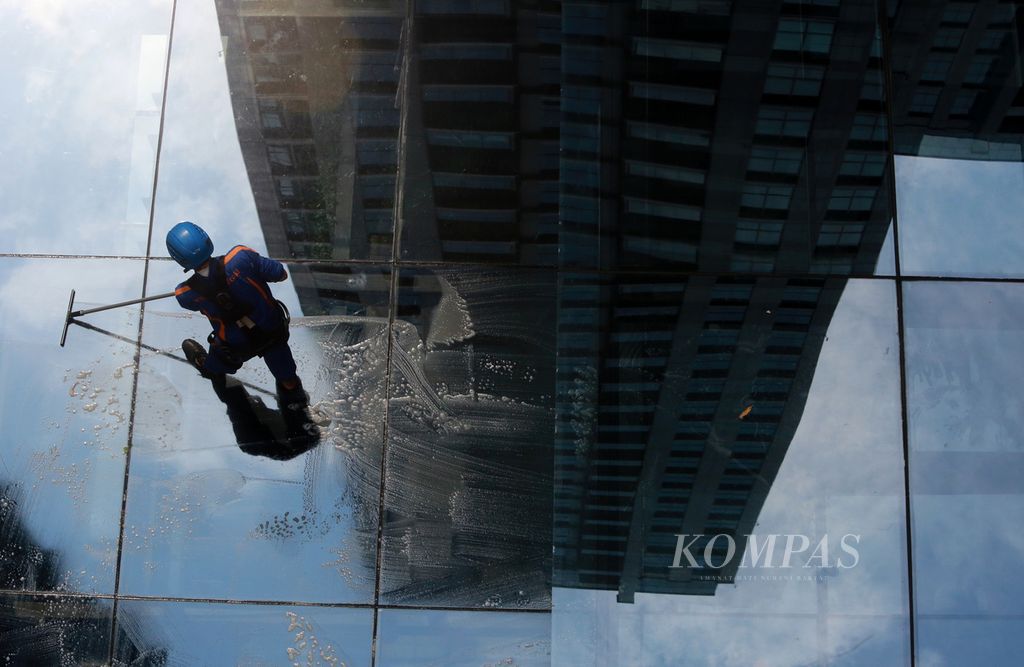 Pekerja membersihkan atap kaca gedung di kawasan Senopati, Jakarta Selatan, Selasa (22/2/2022). 