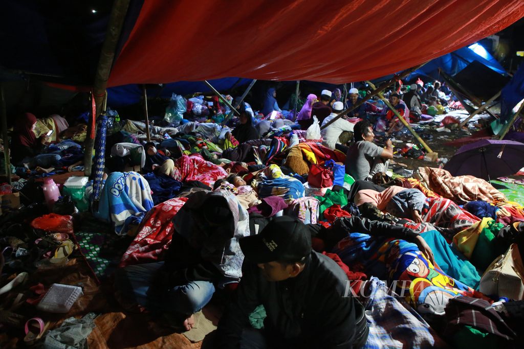 Warga korban gempa bumi bertahan di pengungsian dengan atap terpal seadanya di lapangan di Desa Cibeureum, Kecamatan Cugenang, Kabupaten Cianjur, Jawa Barat, Selasa (22/11/2022) malam. Pengungsian tersebut juga dihuni oleh warga senior, anak-anak, hingga anak balita.  
