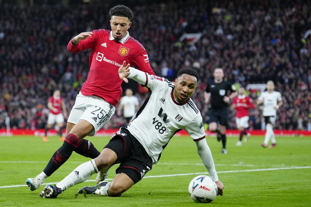 Pemain Fulham Kenny Tete (kanan) dibayangi pemain Manchester United Jadon Sancho pada pertandingan perempat final Piala FA antara Manchester United dan Fulham di Stadion Old Trafford, Manchester, Minggu (19/3/2023).