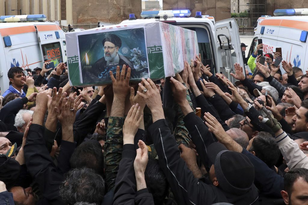 Warga Iran berupaya menggapai peti jenazah Presiden Iran Ebrahim Raisi dalam upacara di kota Tabriz, Iran, Selasa (21/5/2024).