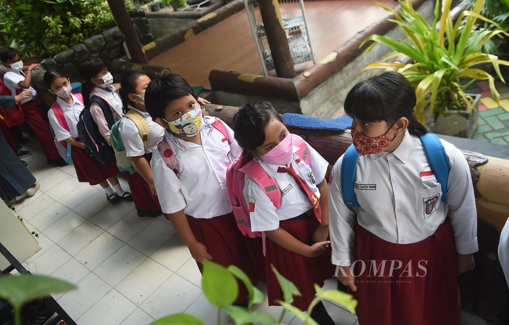 Siswa antre saat keluar kelas saat pulang sekolah di SD Negeri Kaliasin 01, Surabaya, Jawa Timur, Senin (10/1/2022). Pemerintah Kota Surabaya mulai melaksanakan pembelajaran tatap muka atau PTM 100 persen bagi PAUD, TK, SD dan SMP pada 10 Januari 2022 ini. 