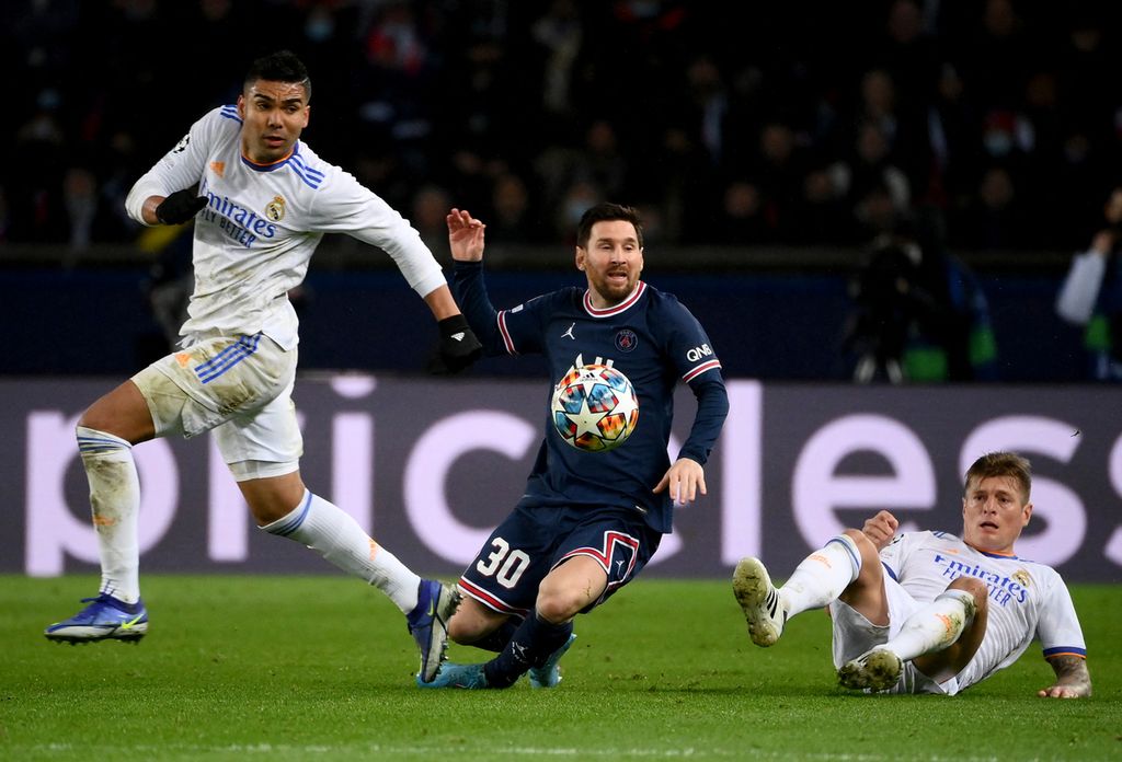 Penyerang Paris Saint-Germain, Lionel Messi (tengah), berusaha melewati hadangan gelandang Real Madrid, Casemiro (kiri) dan Toni Kroos, pada laga pertama babak 16 besar Liga Champions di Stadion Parc des Princes, Paris, Perancis, Rabu (16/2/2022) dini hari WIB. Messi mempunyai peluang emas melalui tendangan penalti pada menit ke-62, tetapi tendangannya berhasil digagalkan kiper Real Madrid, Thibaut Courtois.