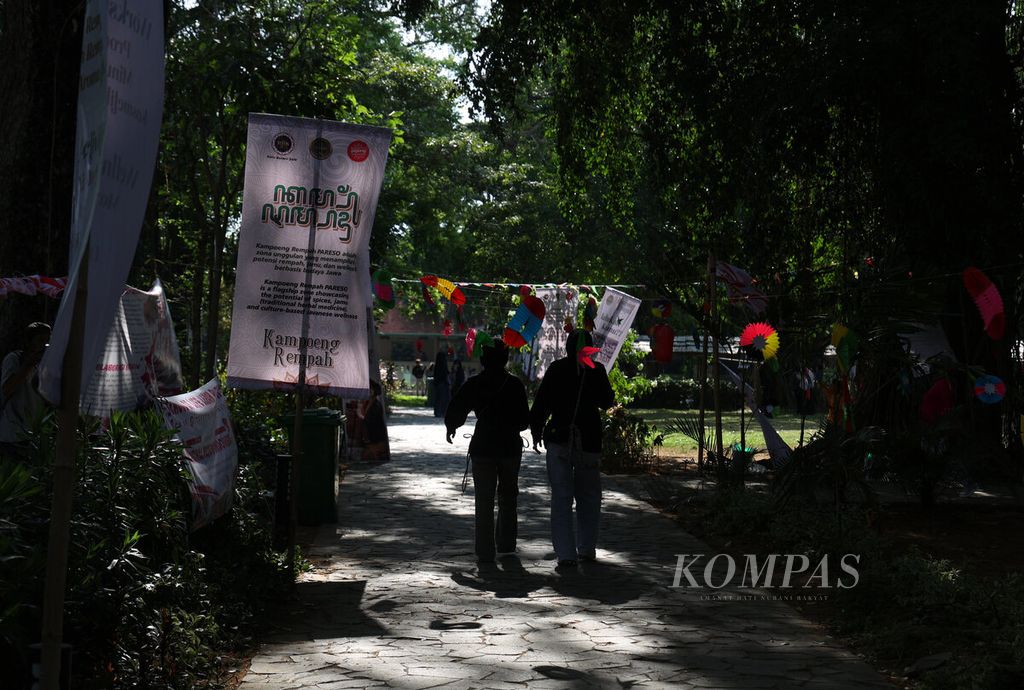 Warga berjalan di antara pohon besar yang menaungi tempat penyelenggaraan Festival Payung Indonesia 2025 di Taman Balekambang, Kota Surakarta, Jawa Tengah, Sabtu (6/9/2025). 