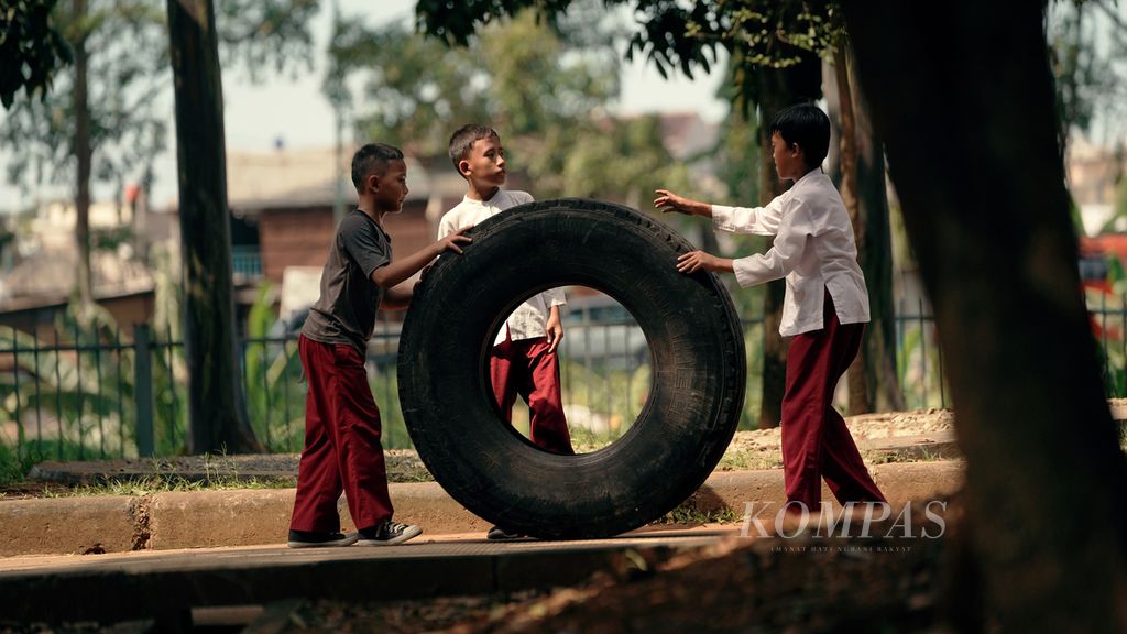Pelajar sekolah dasar bermain ban truk sepulang sekolah di Kanal Timur, Duren Sawit, Jakarta Timur, Jumat (13/5/2022). Pembelajaran tatap muka 100 persen tiap hari terus didorong. Kini penambahan aktivitas di sekolah diizinkan, mulai dari kegiatan olahraga/ekstrakurikuler di ruang terbuka hingga pembukaan kantin sekolah secara terbatas.
