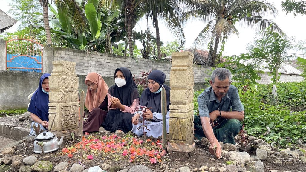 Supriani (second from right) with family members visits the grave of his daughter-in-law Julia Ningsih (19), at the Dasan Borok Village Public Cemetery, Suralaga District, East Lombok Regency, West Nusa Tenggara, Friday (21/1/2022). Julia Ningsih, who left for Malaysia with Junaidi, her husband, was one of the victims who died in a non-procedural Indonesian Migrant Worker ship accident in the waters of Johor, Malaysia, in mid-December 2021.