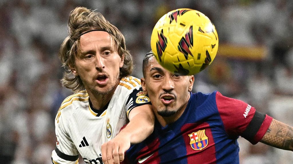 Pemain Barcelona Raphinha (kanan) berebut bola dengan pemain Real Madrid Luka Modric pada laga Liga Inggris di Stadion Santiago Bernabeu, Madrid, 21 April 2024.