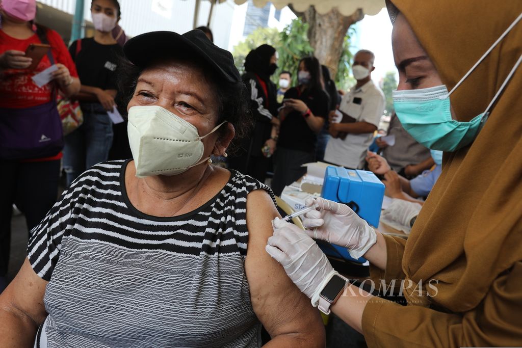 An elderly woman gets an injection of the Covid-19 booster vaccine to residents in the courtyard of the DKI Jakarta City Hall, Tuesday (24/1/2023).