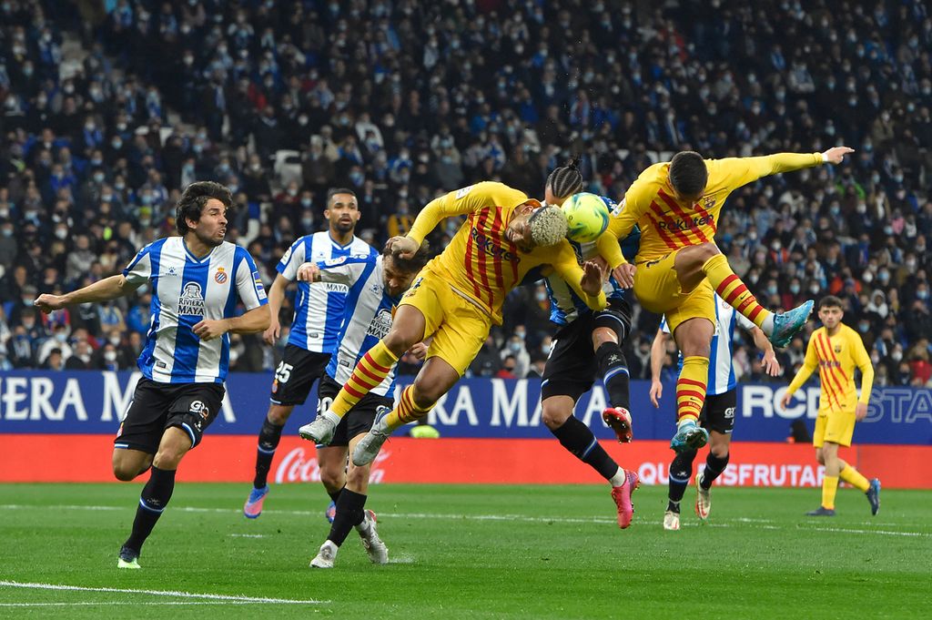Bek Barcelona, Ronald Araujo (kiri), berjibaku dengan penyerang Espanyol, Raul de Tomas (tengah), dalam lanjutan Liga Spanyol di Stadion Cornella-El Prat, Barcelona, Spanyol, Senin (14/2/2022) dini hari WIB. Barcelona sempat unggul cepat pada menit kedua melalui sontekan Pedri memanfaatkan asis sempurna Jordi Alba dari sisi kiri pertahanan tuan rumah.
