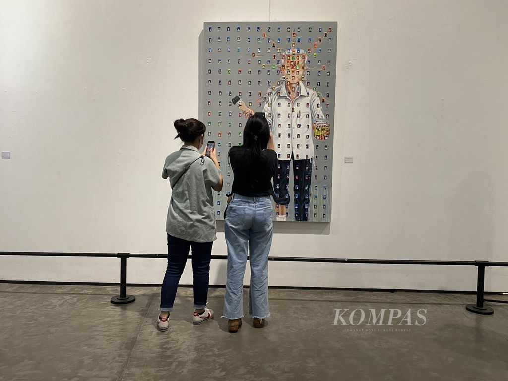 Pengunjung memotret salah satu karya seni yang dipamerkan dalam pameran seni rupa bertajuk Seni Agawe Santoso di Semarang Contemporary Art Gallery, Kota Semarang, Jawa Tengah, Kamis (23/2/2023). Sebanyak 65 lukisan yang dibuat oleh 45 seniman asal Jateng dan Daerah Istimewa Yogyakarta itu diharapkan bisa menginspirasi semua pihak untuk mengupayakan kesentosaan dalam kehidupan berbangsa, terutama jelang tahun politik.